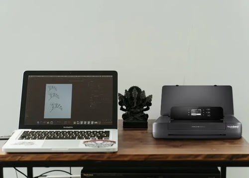 PS-M200 sitting on a desk next to a laptop 