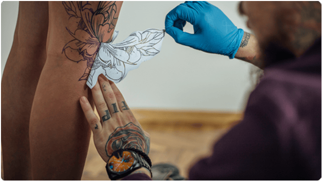 Tattoo artist taking stencil off of client
