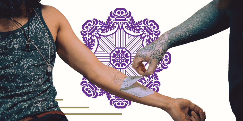 Tattoo artist putting tattoo stencil on a customers arm