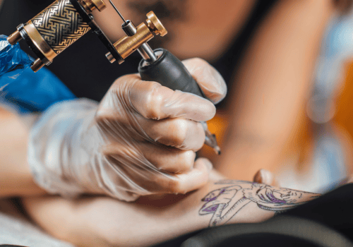 Tattoo-artist-applying-ink-to-a-stencil-on-someones-arm