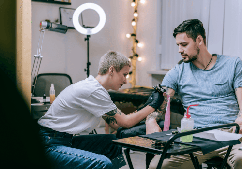 tattoo-artist-tattooing-a-man-in-her-shop